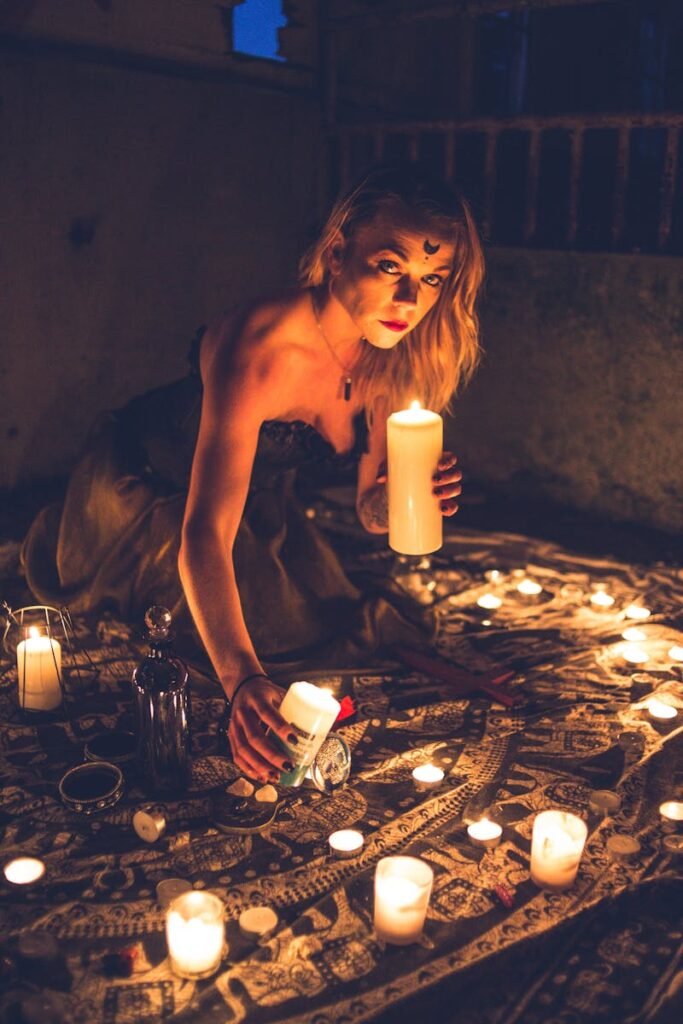 A woman performing a ritual surrounded by candles in a dimly lit room, evoking mysticism and intrigue.